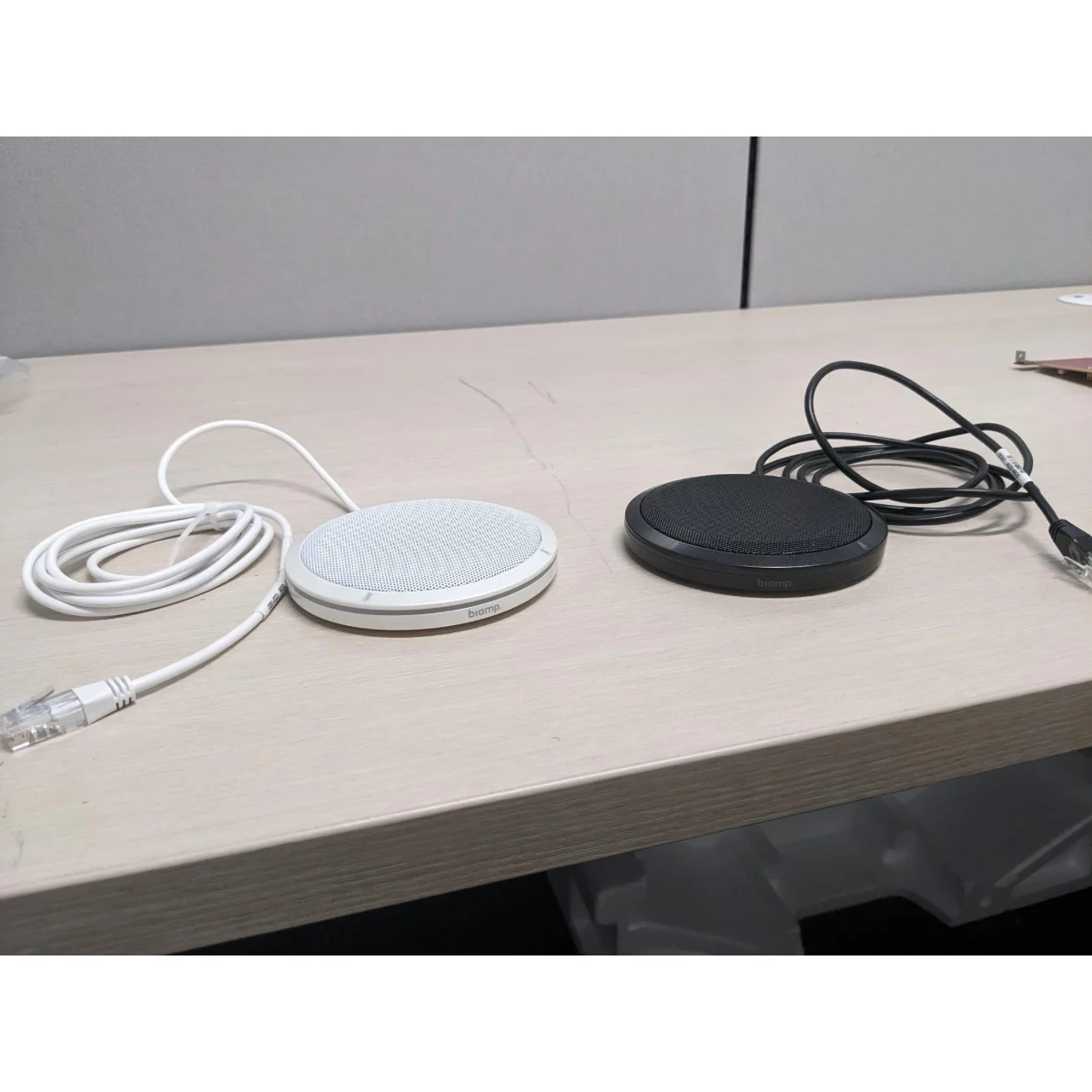 Micro để bàn Biamp Parlé TTM-XEX màu trắng và đen đặt trên bàn, kèm cáp kết nối